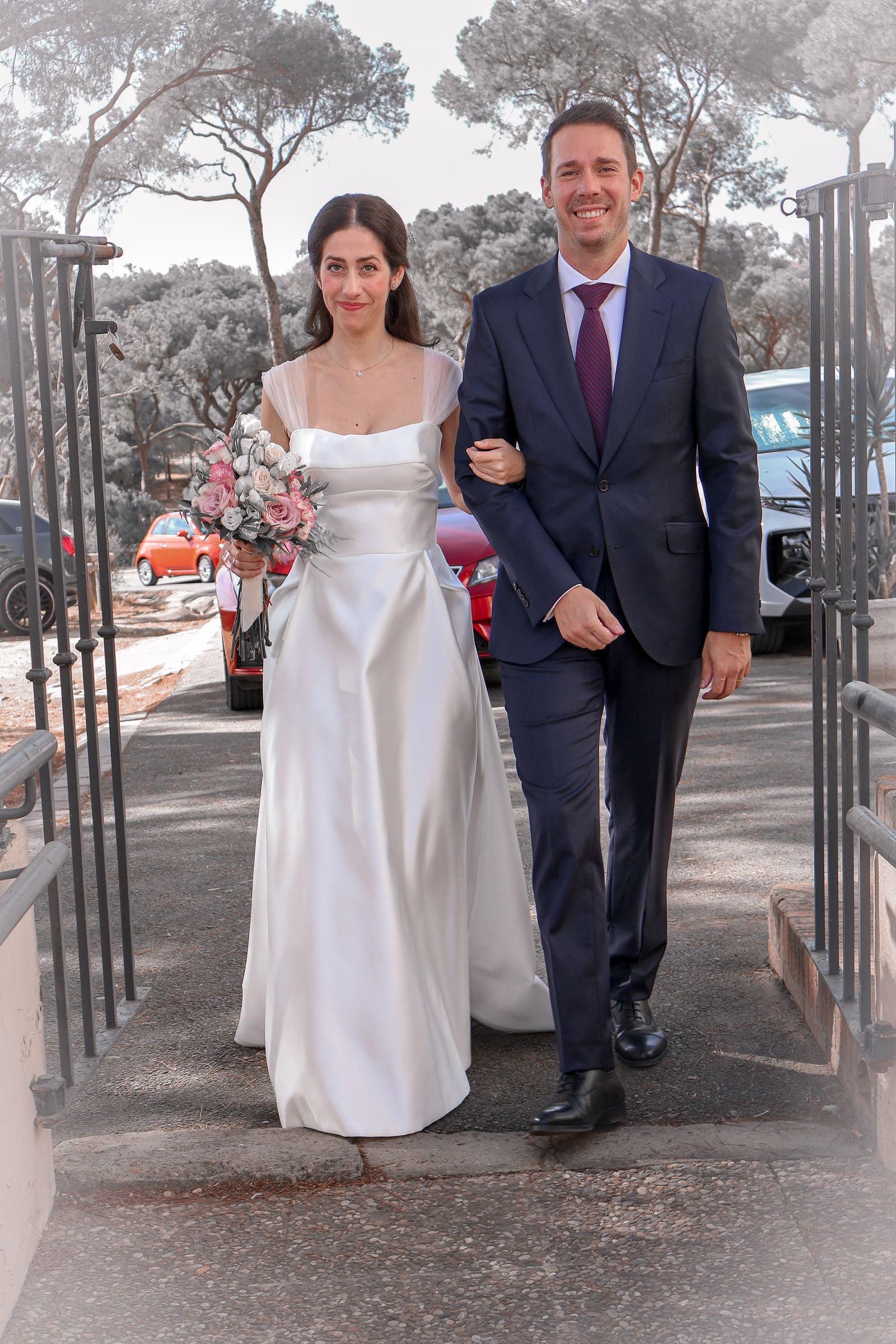 La novia llega a la ceremonia del brazo de su acompañante, con el ramo en la mano.