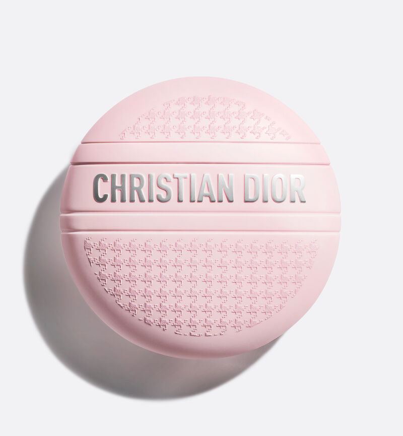 Base. Packshot de un bote de crema rosa sobre fondo gris y, generado con IA, el mismo bote entre sábanas y almohadas blancas.