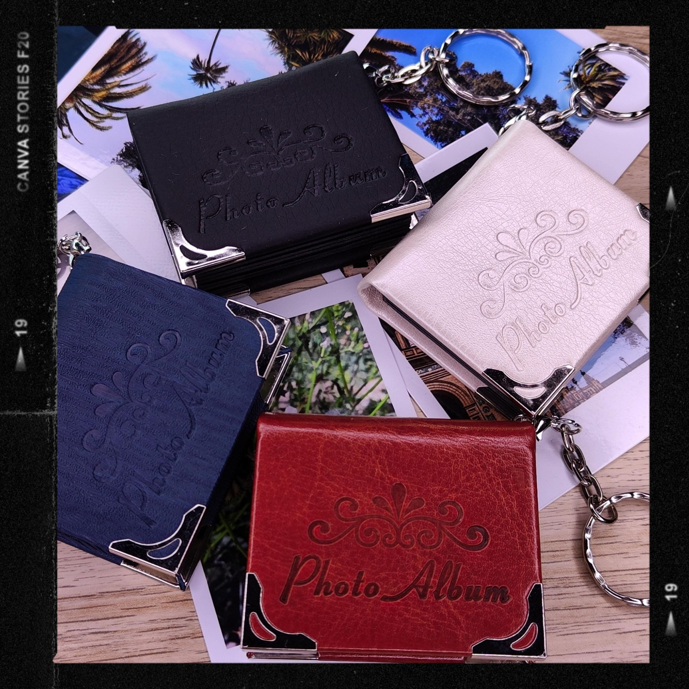 Fotografía de producto: cuatro llaveros álbum —negro, blanco, azul y rojo— sobre fotos impresas, en un marco de negativo.