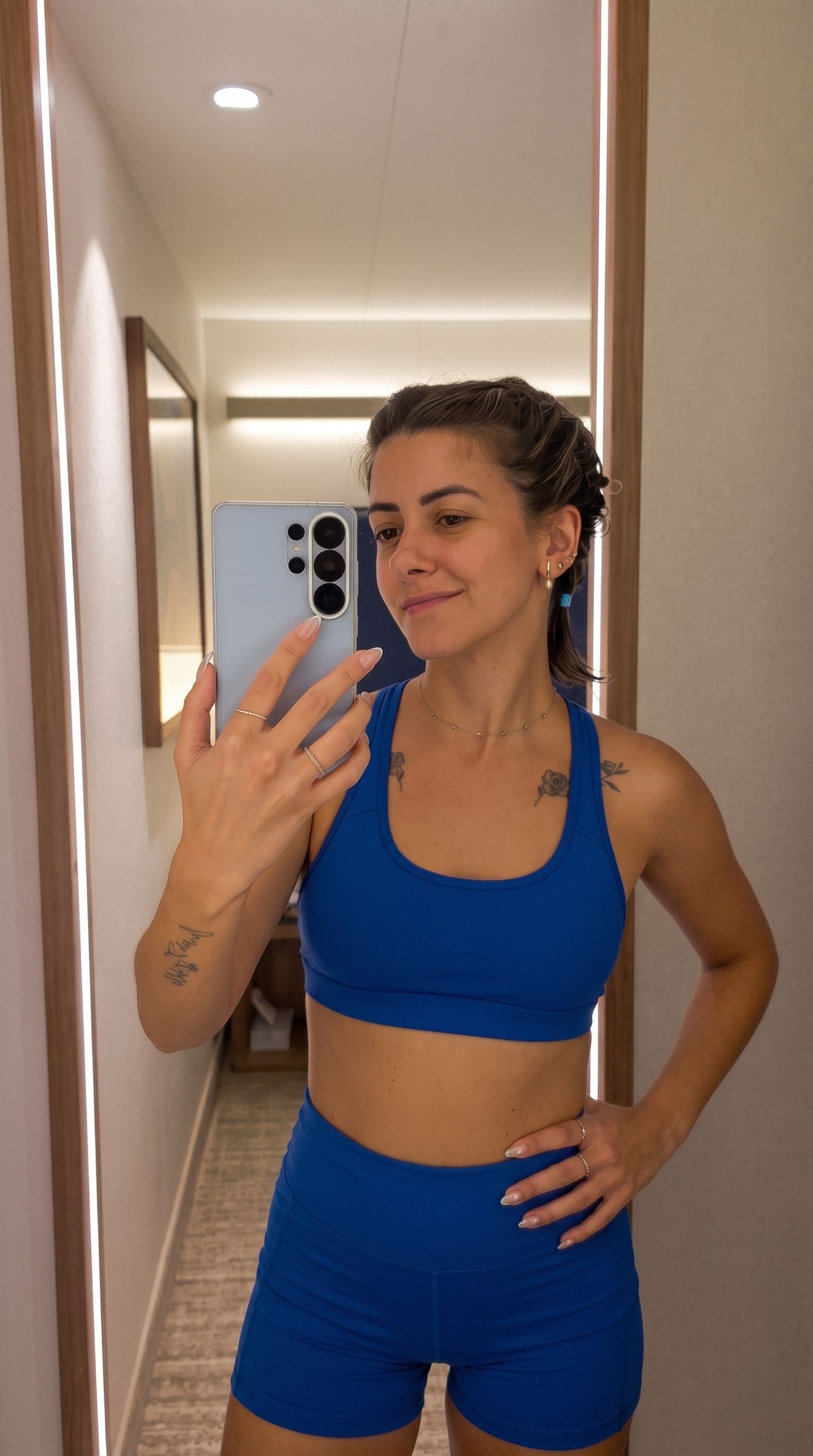 IA. Selfie de probador con un conjunto de lino azul y, tras la edición con IA, la misma foto con sujetador deportivo y short azul eléctrico.