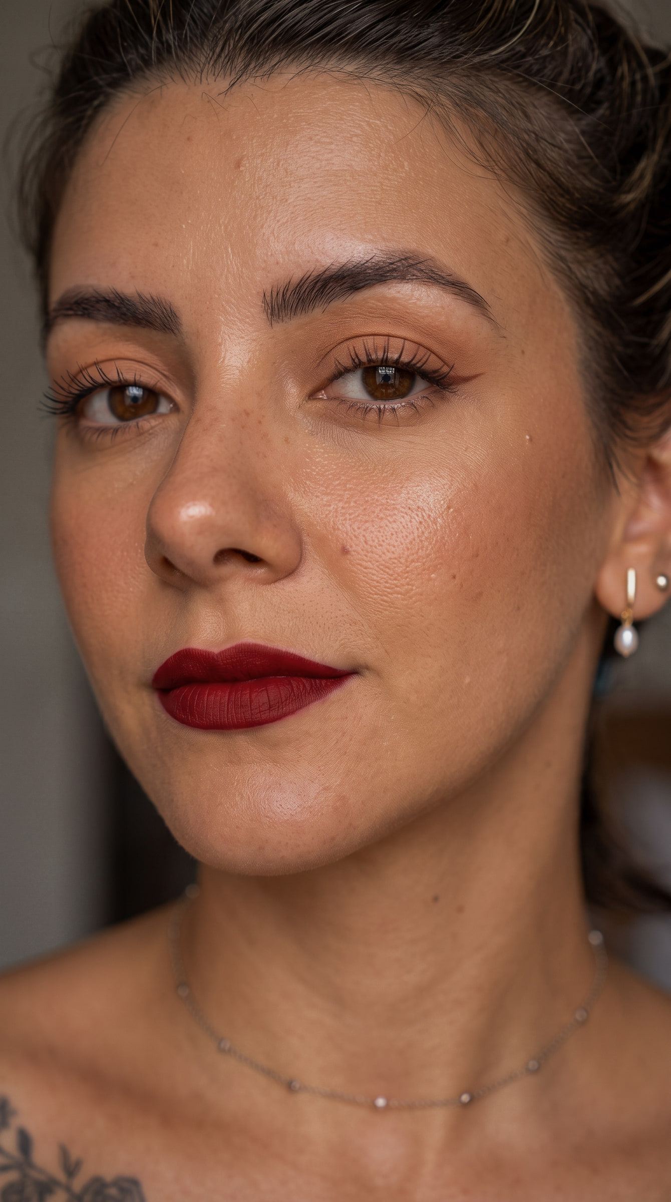 Primer plano con sombra melocotón, pestañas definidas y labio burdeos mate.