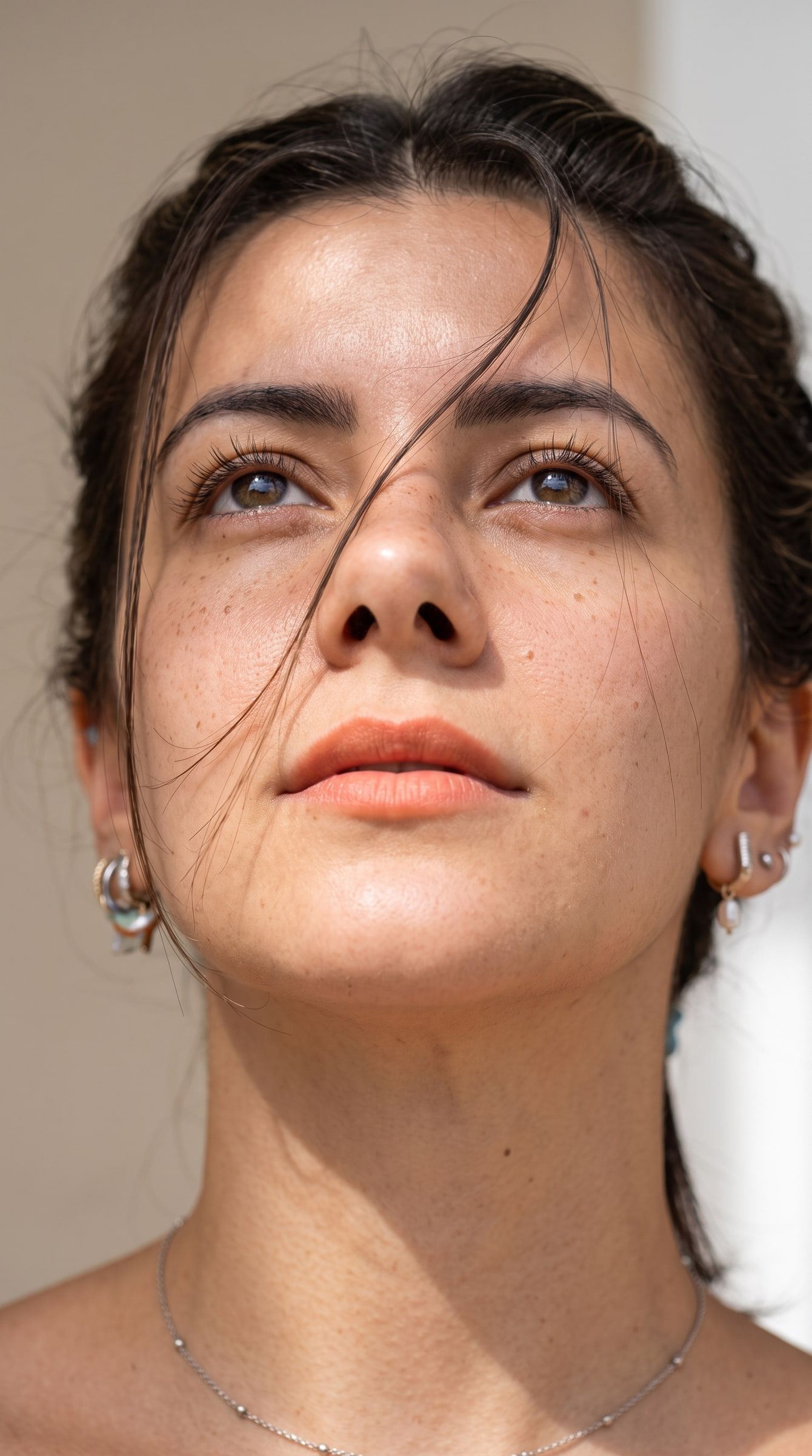 Primerísimo plano a pleno sol con piel natural, pecas y mechones sueltos sobre la cara.