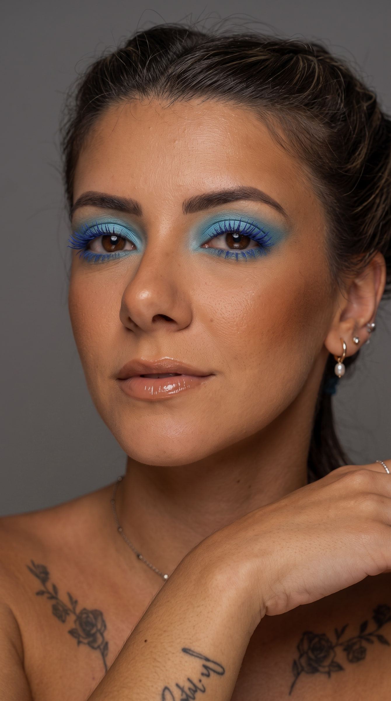 Retrato de estudio con sombra y máscara azul eléctrico, piel bronceada y labio nude con brillo.